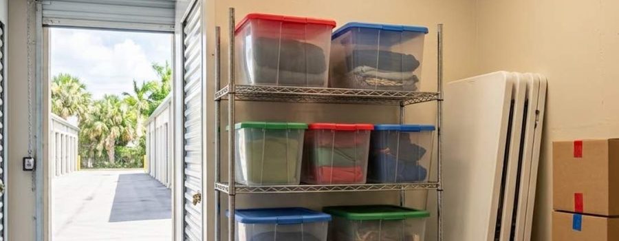 Organized climate controlled storage unit with stacked donation boxes, folding tables, and event supplies for a local charity.